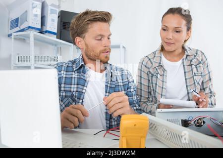 electricians using multimeter to diagnose fault with heater Stock Photo