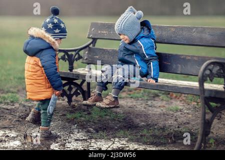 Two little boys is covered in mud and dirt in a swamp at the park. He is very unclean as he learns about nature and outdoors. Both children are happy Stock Photo