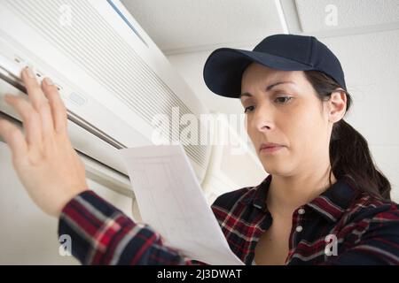 woman following instructions to programme air conditioning unit Stock Photo