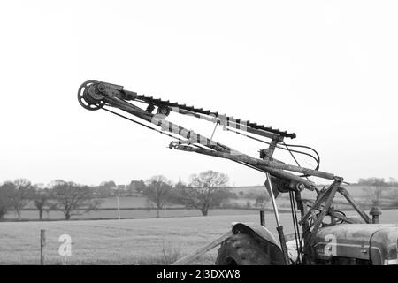 An old antique hedge trimmer mounted on a vintage tractor Stock Photo