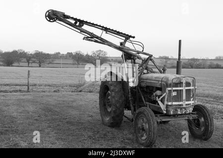 An old antique hedge trimmer mounted on a vintage tractor Stock Photo