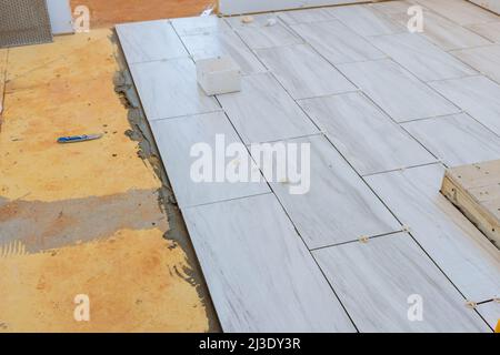 The process of laying ceramic tiles on glue smeared floors Stock Photo