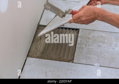 Man installs placing the ceramic tile over floor Stock Photo