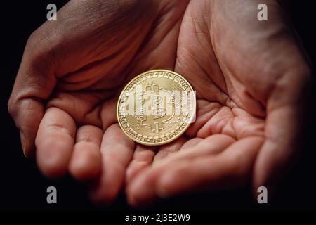 Close up shot of hands holding a golden bitcoin digital cryptocurrency. Stock Photo