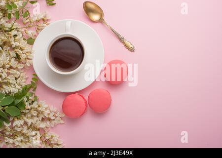 Spring floral background with coffee and macaroons, textures and wallpaper. Flat white flowers on a light pink background, top view, copy space. Festi Stock Photo