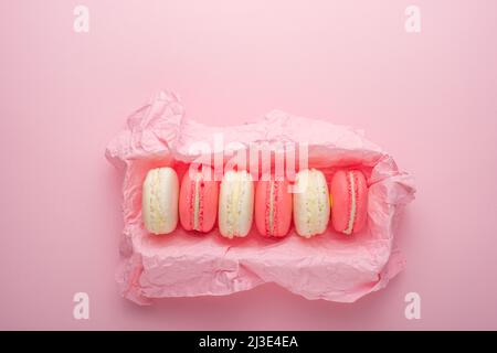 Macaroons in a box on a light pink background, flatlays, with an empty space for writing on a postcard or congratulations Stock Photo