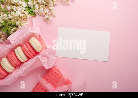 Macaroons in a box on a light pink background with a gift, flatlays, with an empty space for an inscription or congratulations on a holiday, a woman o Stock Photo