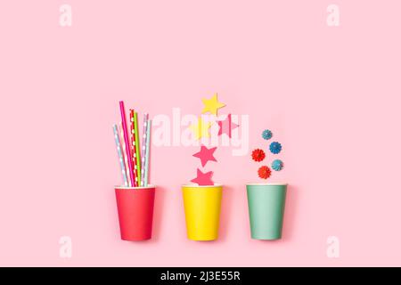 Colored drinking straws, paper stars and meringues in colored paper glass on a pink background Stock Photo