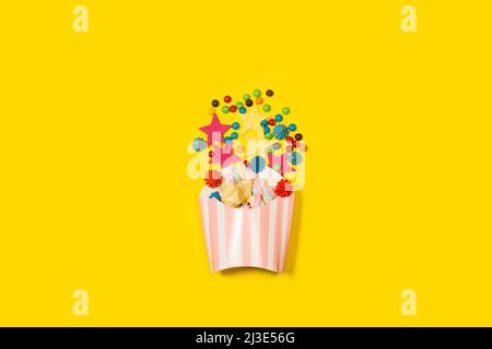 Colored meringues and candies in a striped bucket and on a yellow background with copy space Stock Photo
