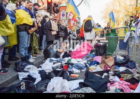 London, UK. 7th April 2022. Protesters stand next to piles of clothes and other items thrown on the ground during the demonstration. Hundreds of people gathered outside the Russian Embassy and dumped pans, clothing, toys, appliances and other household items, in response to the looting by Russian soldiers in Ukraine. Credit: Vuk Valcic/Alamy Live News Stock Photo