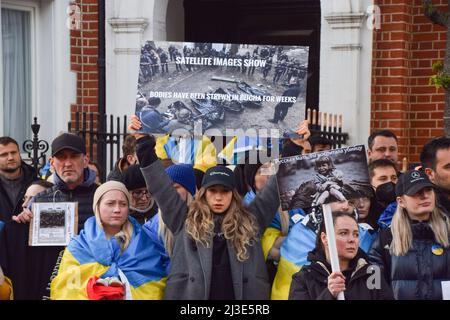 London, UK. 7th April 2022. A protester holds a picture of dead bodies in Bucha. Hundreds of people gathered outside the Russian Embassy and dumped pans, clothing, toys, appliances and other household items, in response to the looting by Russian soldiers in Ukraine. Credit: Vuk Valcic/Alamy Live News Stock Photo