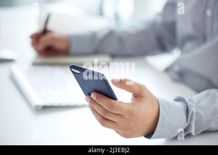 Planning is always a priority if you want to succeed. Closeup shot of an unrecognisable businessman using a cellphone while writing notes in an office Stock Photo