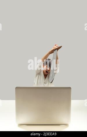 To the fight! Infernal machine I will prevail! Woman fights with her laptop with a medieval sword. Concept of frustration with computers and technolog Stock Photo