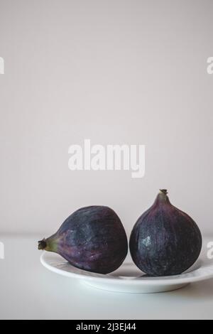 Fresh ripe whole figs minimalism. Juicy figs on the plate on grey background Stock Photo
