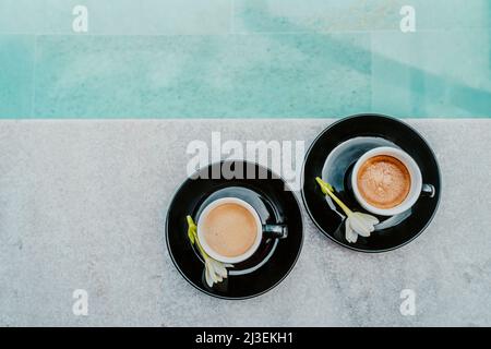 Coffee in espresso cups for two people on luxury pool side on vacation. High end resort hotel. Top view of mugs Stock Photo