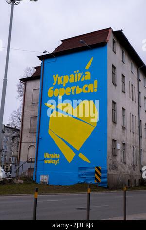 Gdansk Poland March 2022 UKRAINE FIGHTING text IN GRAFFITI with big heart in ukrainian flag colors. Mural painted in building house Poland Gdansk Europe Concept of solidarity and support with Ukraine Stock Photo