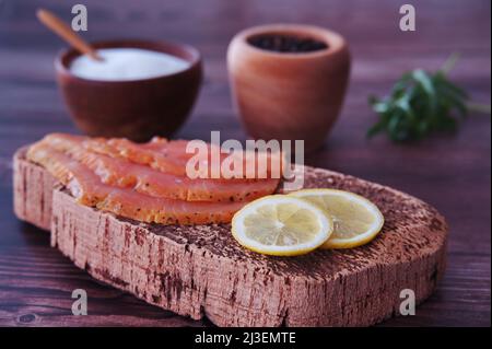 Smoked salmon on a wooden cutting board, garnished with herbs and ...