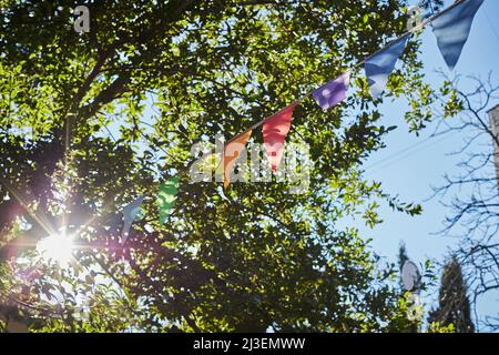 Festive fabric garlands against the blue sky in summer. The concept of celebration, rest, joy and happiness. Front view. Stock Photo