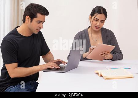 Couple working from home using laptop and digital tablet Stock Photo