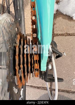 Blue bike has been outside all winter and got broken. Rusty bicycle chain hangs on sprocket and gear. Stock Photo