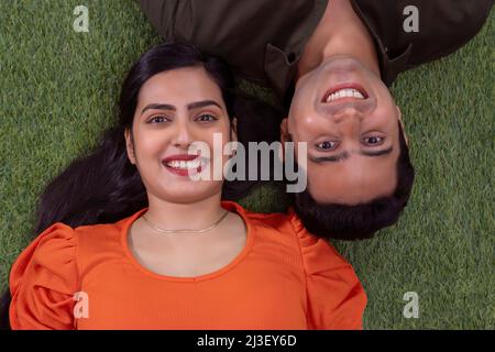 Overhead view of young couple lying on grass Stock Photo