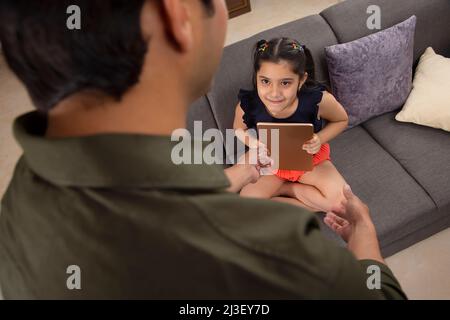 Someone forcibly taking digital tablet from little girl Stock Photo