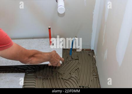 A male construction worker installs a ceramic tile Stock Photo