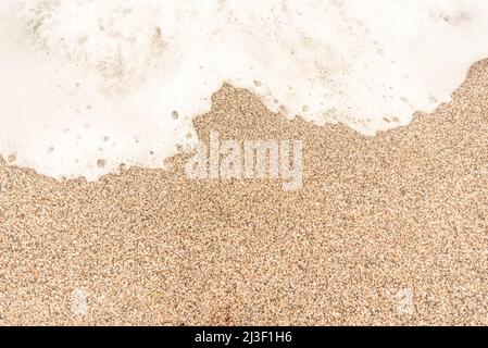 Coarse sand on beach with sea foam Stock Photo
