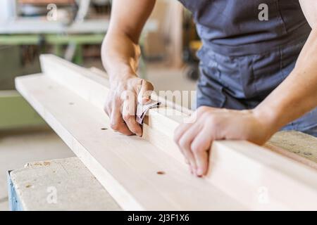 Crop artisan sanding wooden board in workshop Stock Photo