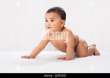 Cute baby in diaper crawling on bed Stock Photo