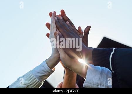 Only great things can happen from here on. Closeup shot of a group of unrecognisable students high fiving on graduation day. Stock Photo