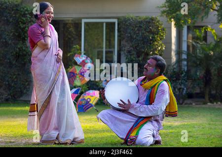 Happy middle aged couple enjoying Holi festival by playing drum and dancing Stock Photo