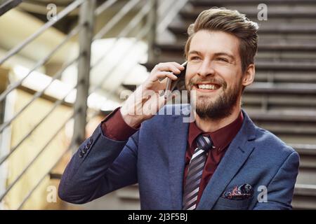 Hes all about style and status. Portrait of a happy young businessman using his phone while out in the city. Stock Photo