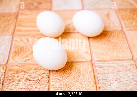 Three eggs on a pink wooden checkered background Stock Photo