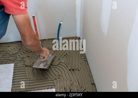 Master puts adhesive base over floor Stock Photo