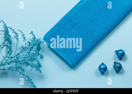 Soft terry towel with decorative branches and toy balls on the blue background. Spa products. Top view. Stock Photo