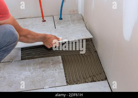 Placing ceramic floor tiles on adhesive surface leveling Stock Photo