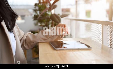 Rear view, Female or businesswoman remote working in the coffee shop, using portable tablet to check her project. Stock Photo