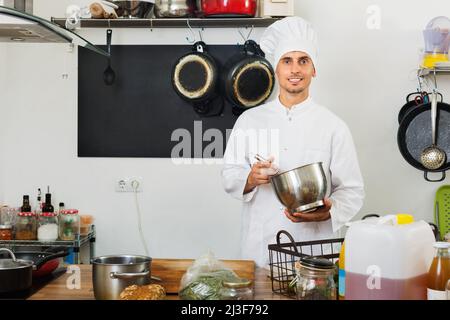 Male cook wearing uniform working on kitchen Stock Photo
