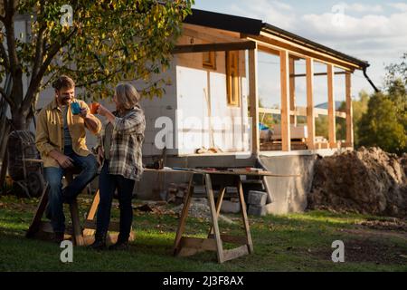 Mature couple having coffee break when working together on construction site of their new house. Stock Photo