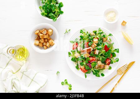 Caesar salad with grilled chicken meat, fresh tomato, croutons, lambs lettuce and parmesan cheese. Healthy lunch. Top view Stock Photo