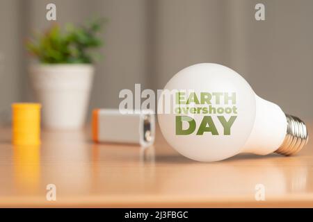 Earth overshoot day concept: light bulb, a battery and an oil barrel on a wooden table Stock Photo