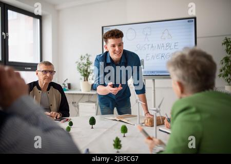 Group of senior students discussing altenrative energy with teacher in classroom. Stock Photo