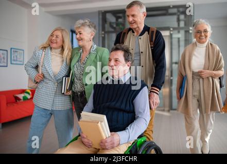 Group of happy senior students walking in corridor in university together. Stock Photo