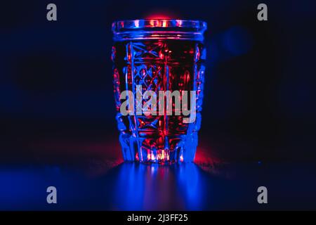 Tincture of red color in a crystal glass in neon lighting Stock Photo