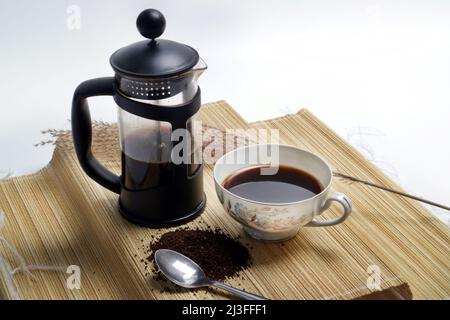 photo studio of french press coffee with cup of coffee and coarse coffee powder on wooden pedestal white background Stock Photo