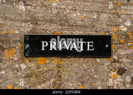 Old mossy stone wall with private plate closeup Stock Photo