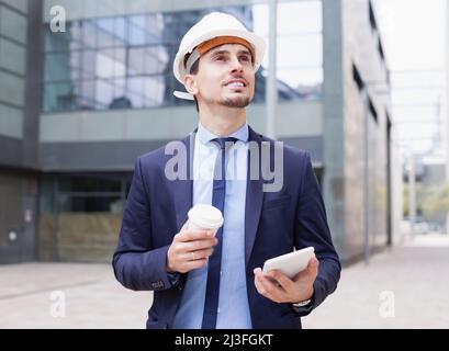 Cheerful architect in helmet working at touchpad Stock Photo