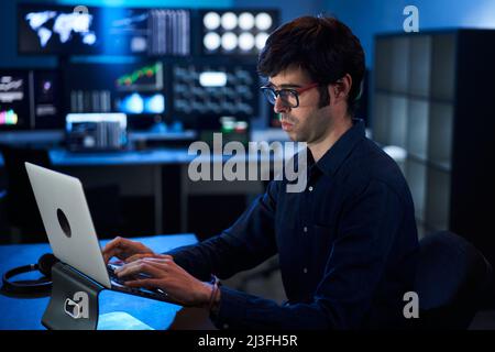 Broker Trader Business Man Working on Laptop in a Corporate Office. Multiple Monitors at Background Stock Photo