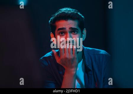 Portrait of a shocked and surprised man while watching horror movie in the movie theater Stock Photo